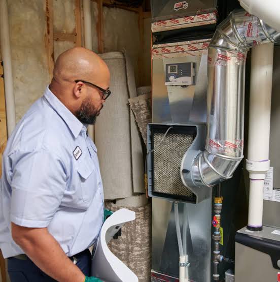 HVAC technician inspecting an indoor furnace and connected ductwork
