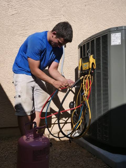 Technician connecting service gauges to a residential outdoor condenser