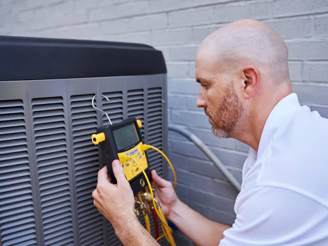 Technician using a handheld diagnostic instrument to check an outdoor air conditioner