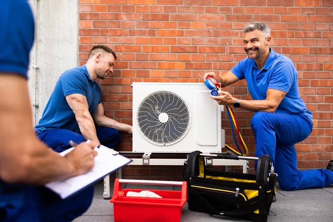 HVAC technicians checking a mini-split system with refrigerant service gauges